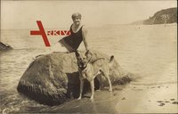 Frau in Badeanzug mit einem Schäferhund am Strand