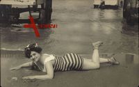 Junge Frau in Badeanzug am Strand im Sand liegend