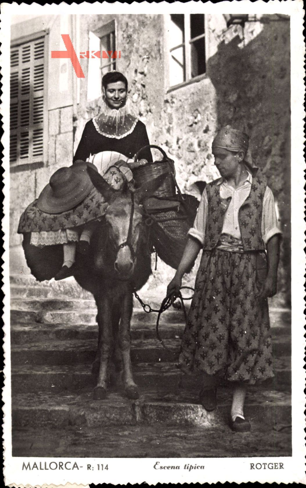 Mallorca, Frau in Tracht mit Korb auf Esel geführt von Mann