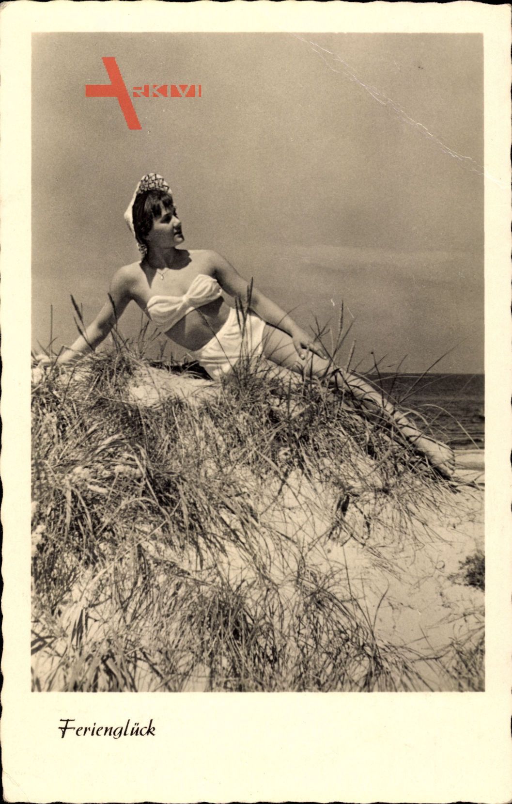 Ferienglück, Junge Frau in Badekleid am Strand liegend